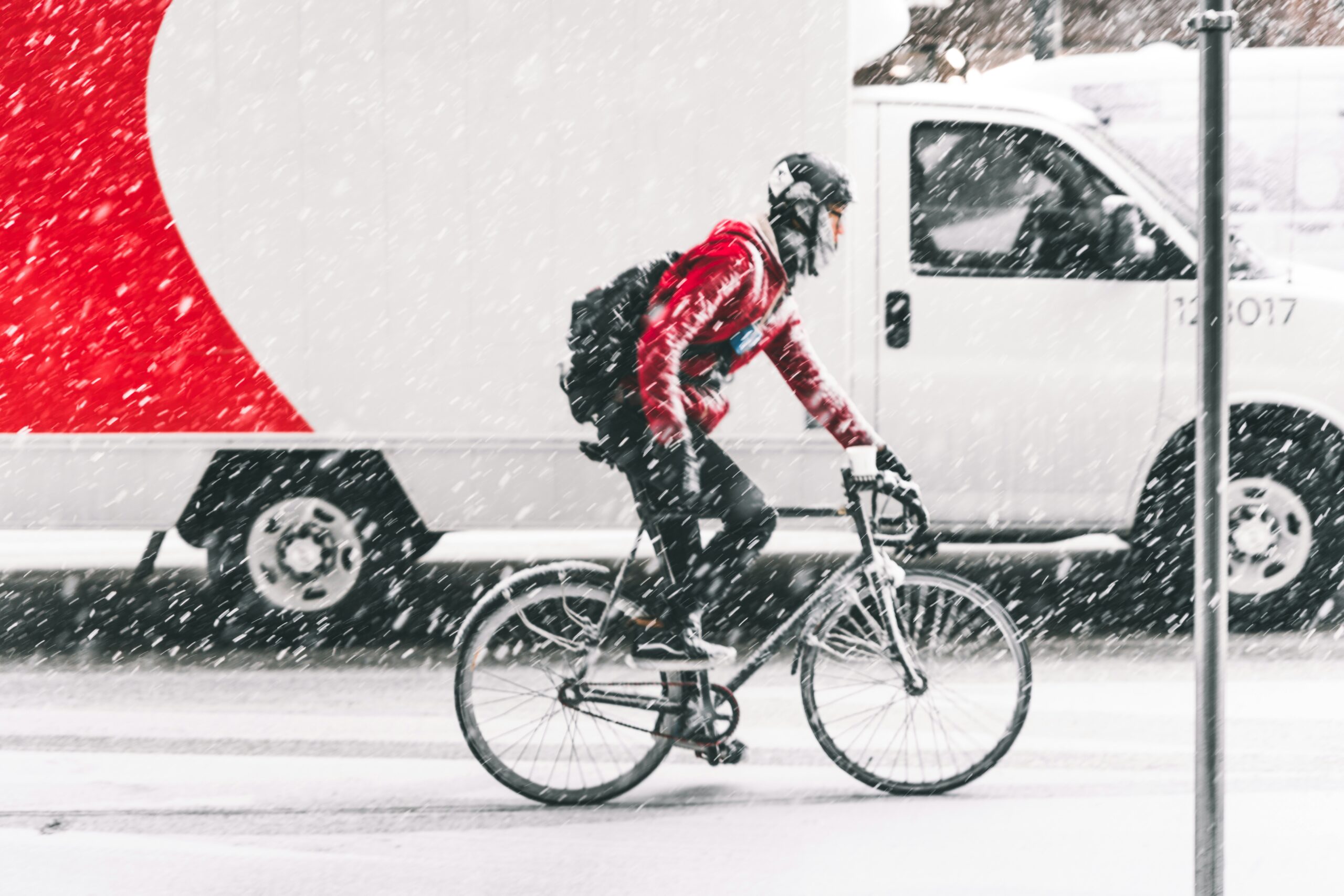 Cyklist på vinterväg med snö och skog i bakgrunden